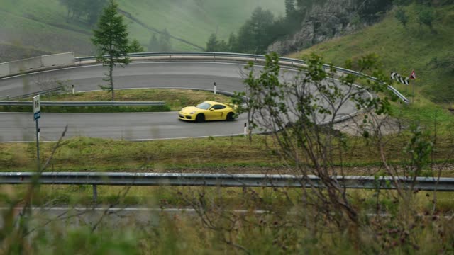 Žlutý Porsche Cayman GT4 v serpentině v Dolomitech Italia Challenge